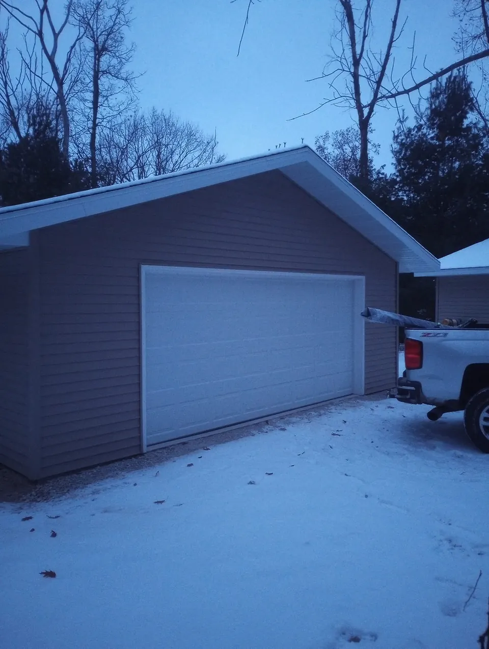 Finished garage with a white door after a light snow