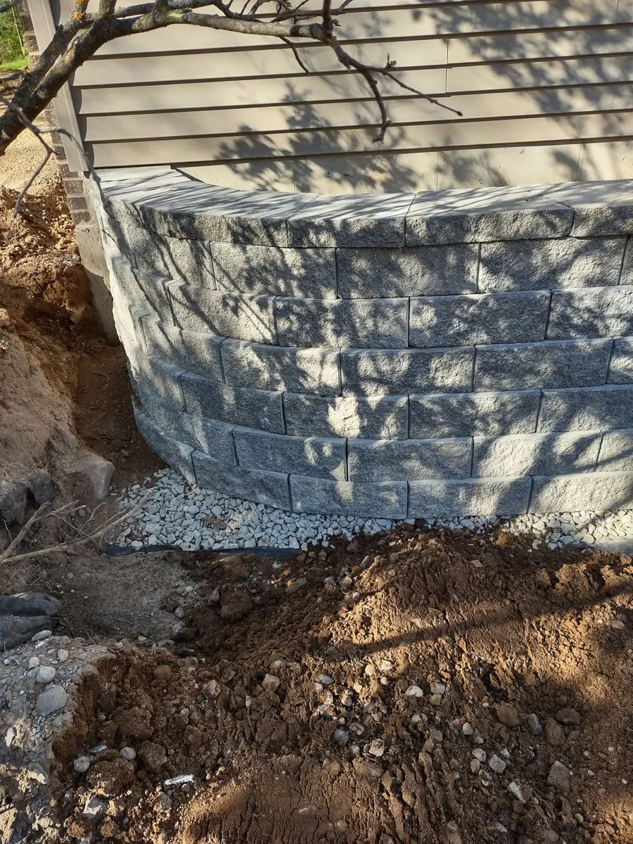 Curved block retaining wall against a house