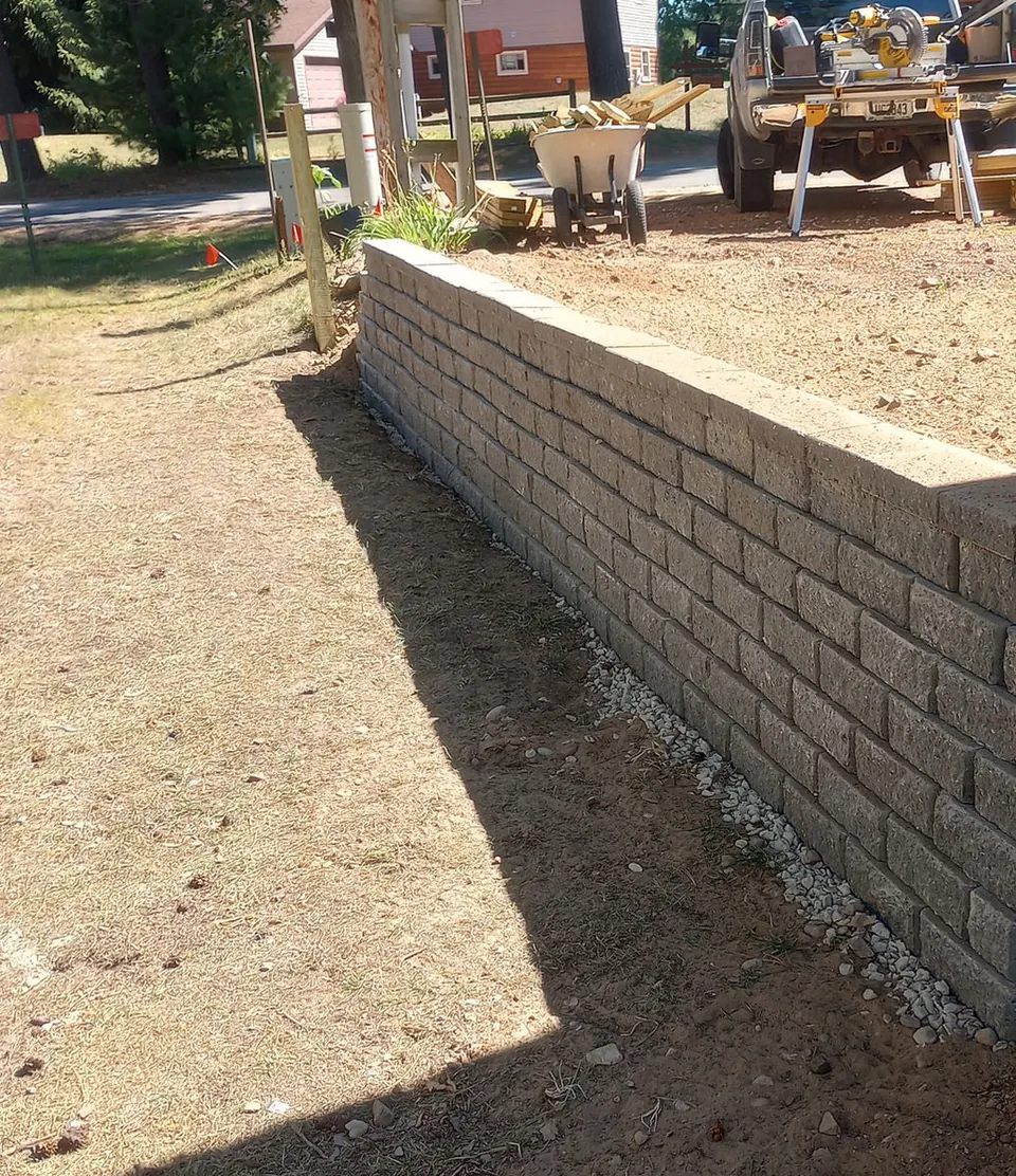 Long block retaining wall with a stone drain bed at its base