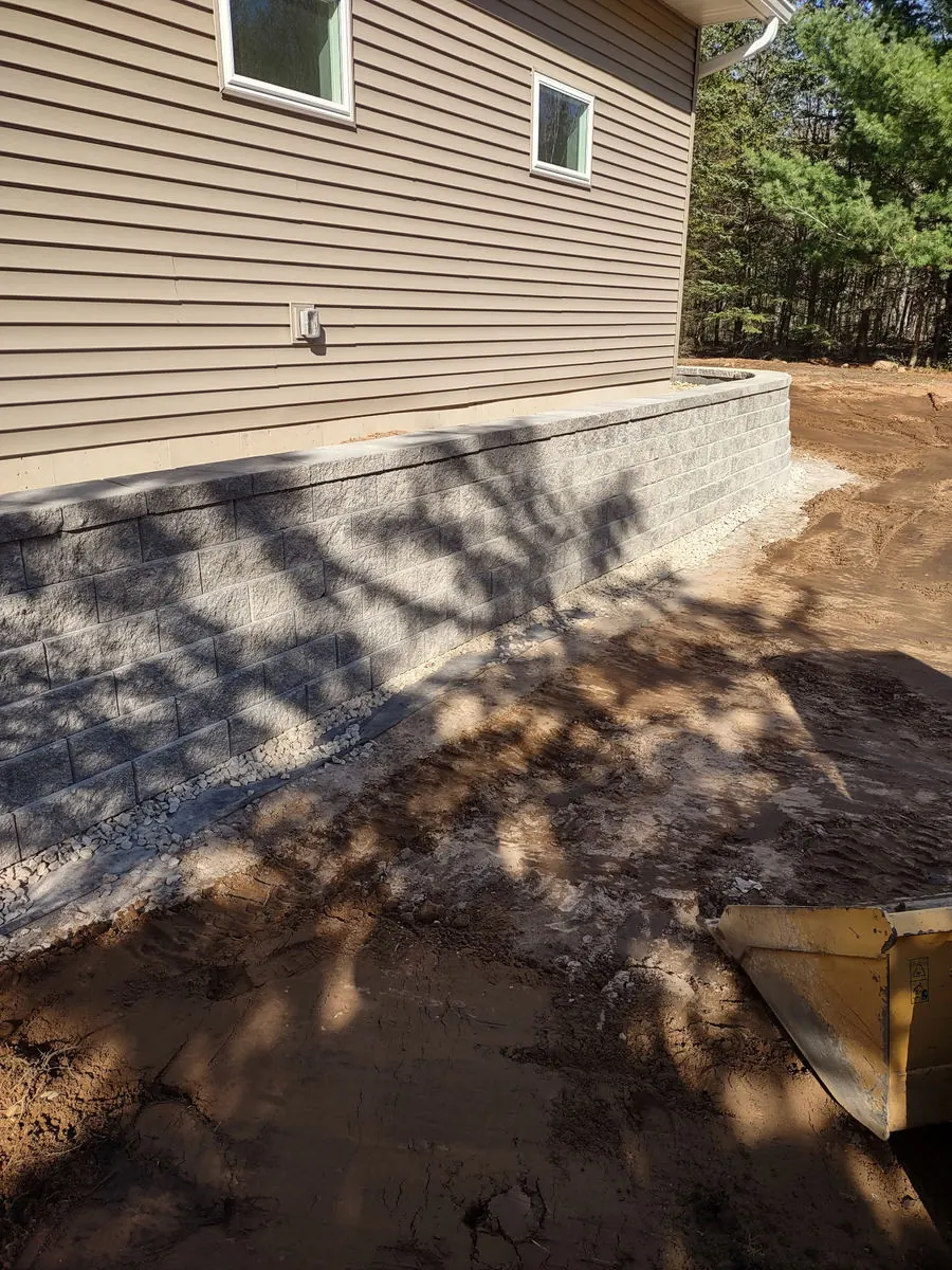 Block retaining wall beside a house with fresh grading